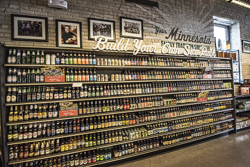 A build your own sixpack sign over a large shelf with many single beers.