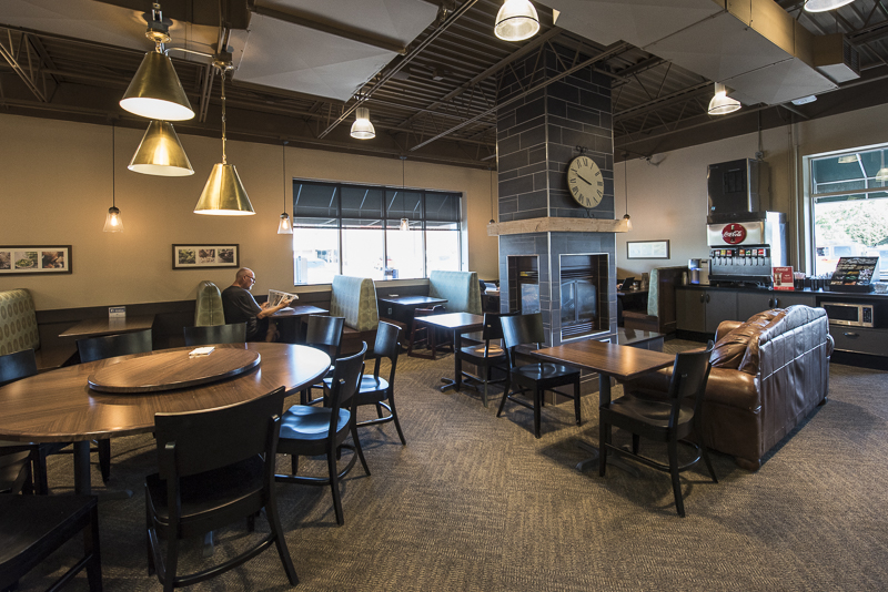 A seating section next to the caribou coffee shop with tables and booths along with a couch and a counter with a fountain drink dispenser.