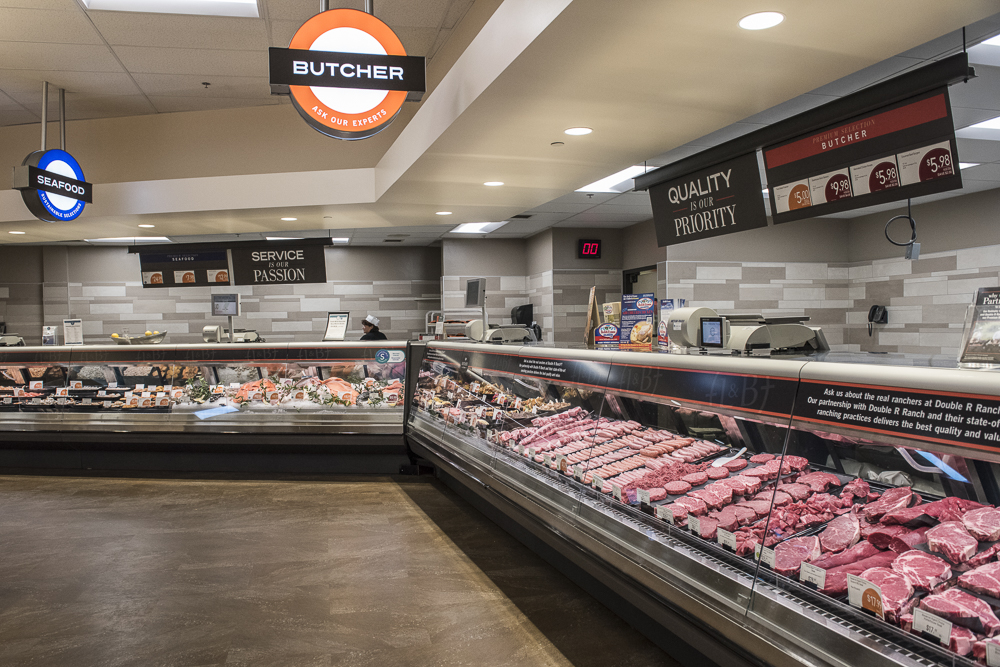 A butcher section with a long counter with meat on display.