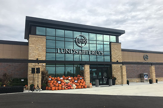 Exterior of store with large glass windows and pumpkins outside.