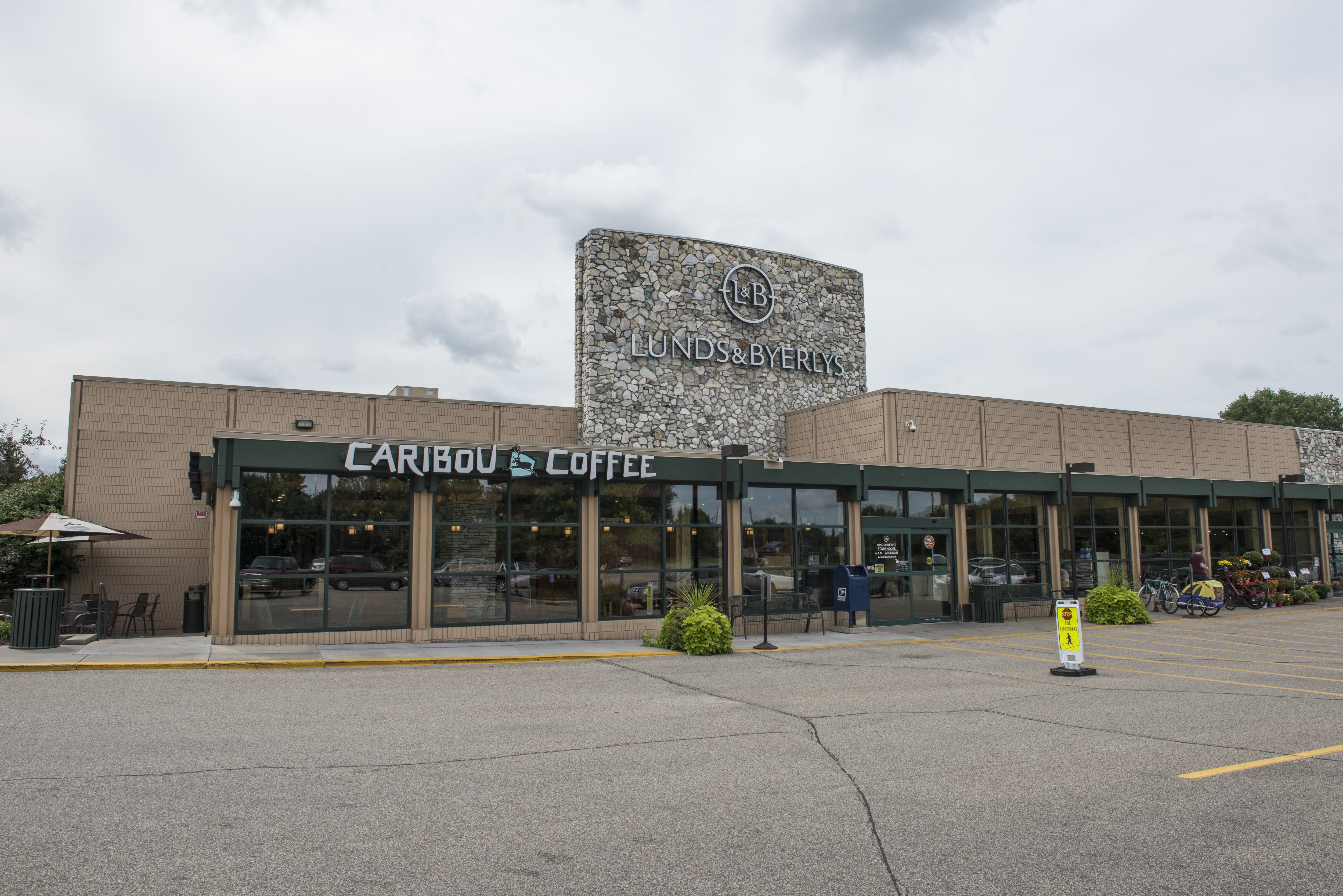 Exterior of store, there is a large stone sign on the roof and you can see the built in Caribou Coffee